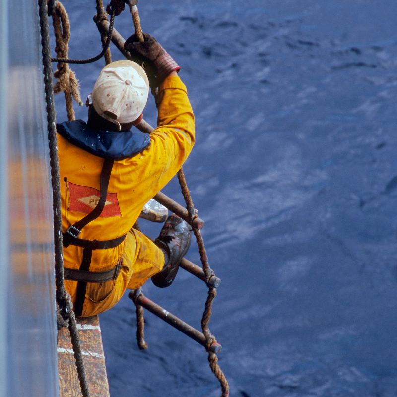 A seaman climbs onto a narrow scaffold