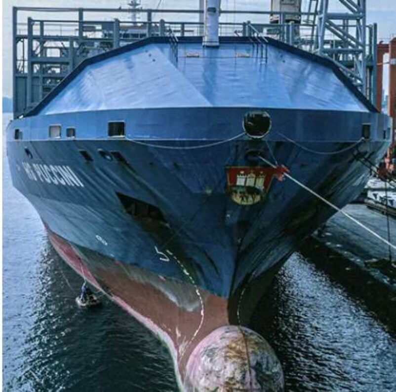 Crew using an inflatable lifeboat to paint the side of their ship.